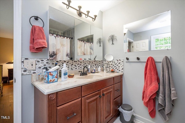 bathroom with baseboards, vanity, decorative backsplash, and wood finished floors