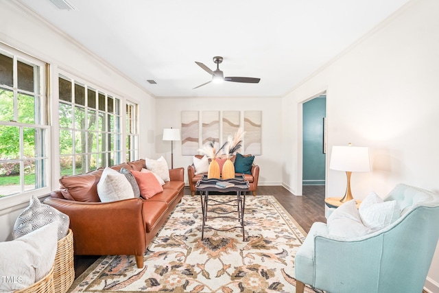 living area with a ceiling fan, baseboards, wood finished floors, visible vents, and ornamental molding