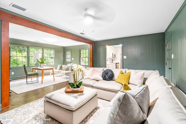 living room with a ceiling fan, visible vents, and wood finished floors
