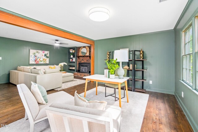 living area with visible vents, a decorative wall, wood finished floors, baseboards, and a ceiling fan