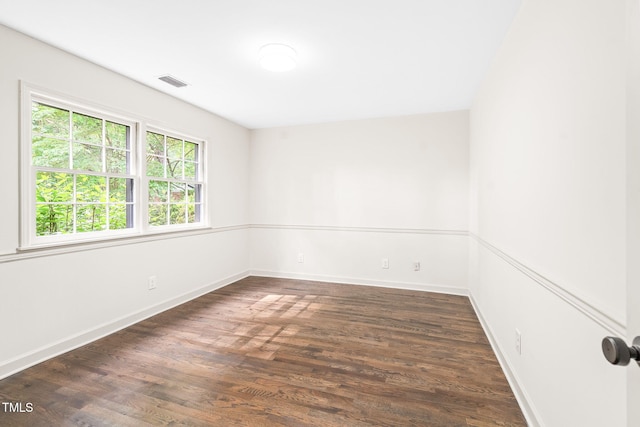 spare room with baseboards, wood finished floors, and visible vents