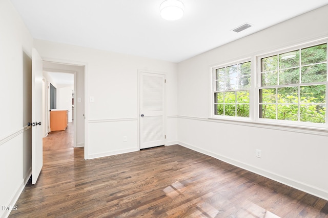 unfurnished room with baseboards, dark wood finished floors, and visible vents