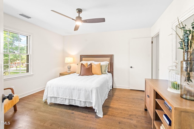 bedroom with baseboards, a ceiling fan, wood finished floors, and visible vents