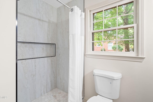 bathroom featuring a shower with shower curtain, a healthy amount of sunlight, and toilet