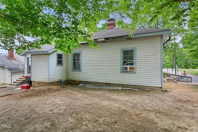 rear view of property featuring entry steps, a chimney, and crawl space