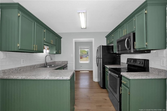 kitchen featuring wood finished floors, light countertops, a sink, backsplash, and stainless steel appliances