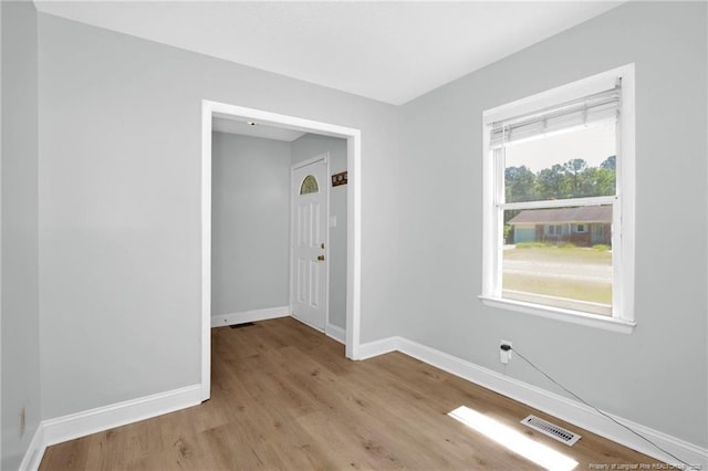 unfurnished room featuring baseboards, light wood-type flooring, and visible vents