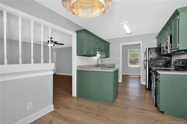 kitchen with appliances with stainless steel finishes, light countertops, baseboards, a sink, and green cabinetry