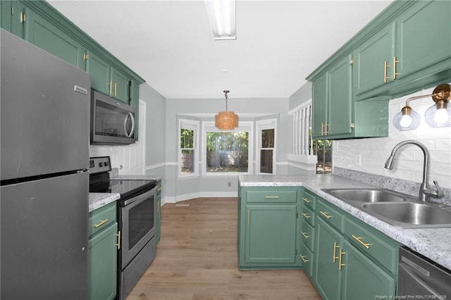 kitchen with pendant lighting, light countertops, a sink, light wood finished floors, and appliances with stainless steel finishes