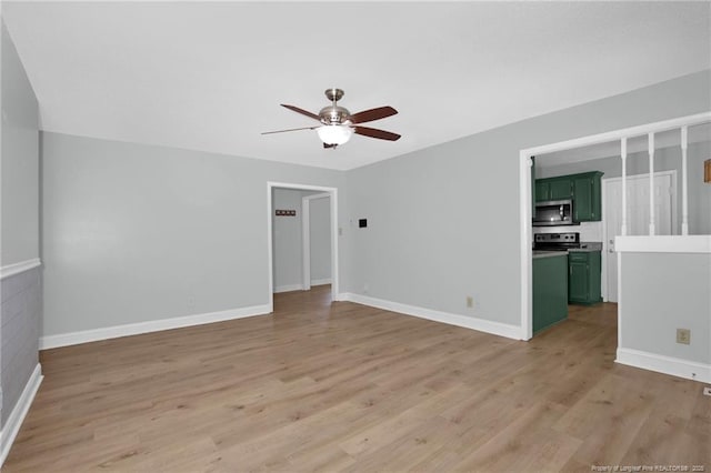 spare room with baseboards, ceiling fan, and light wood finished floors