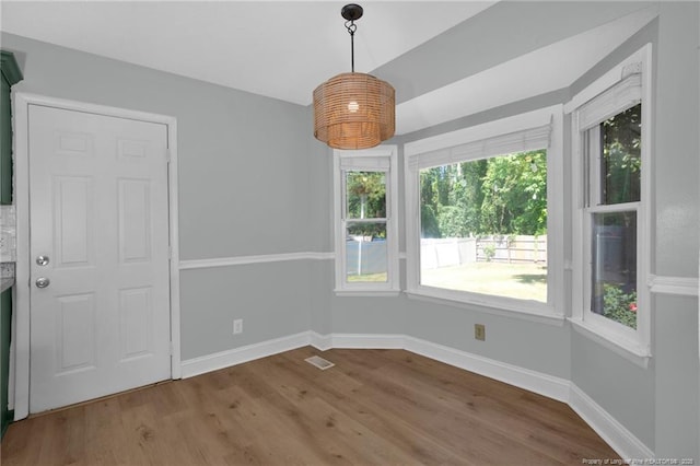 unfurnished dining area with baseboards, wood finished floors, and visible vents