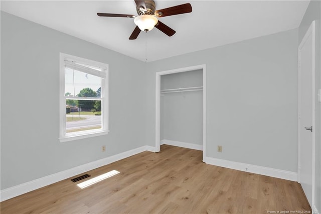 unfurnished bedroom with visible vents, light wood finished floors, baseboards, and a closet