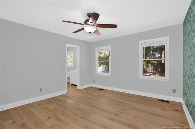 empty room with baseboards, visible vents, a healthy amount of sunlight, and light wood-style floors