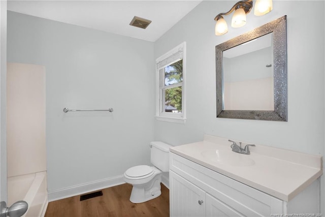 bathroom featuring visible vents, wood finished floors, vanity, baseboards, and toilet