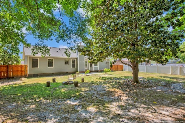 exterior space with a fenced backyard, a lawn, an outdoor fire pit, and crawl space