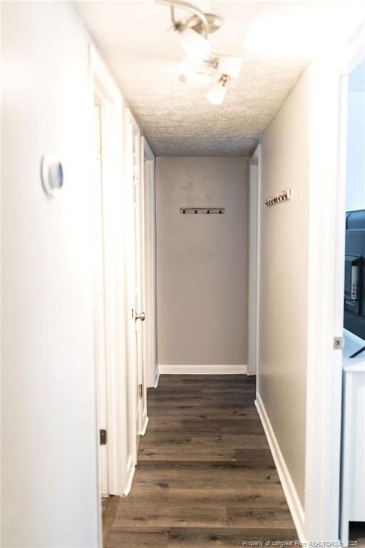 3254 Blossom Dr, Fayetteville, NC 28306 - corridor with a textured ceiling, dark wood finished floors, and baseboards