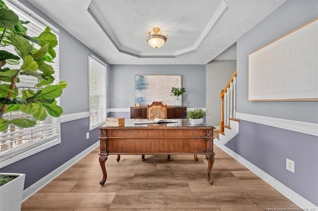 home office featuring baseboards, a tray ceiling, and wood finished floors
