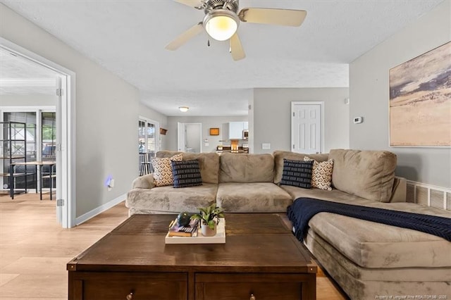 living room with a ceiling fan, baseboards, visible vents, and light wood-style flooring