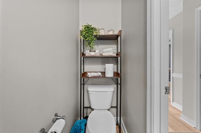 bathroom with baseboards, wood finished floors, and toilet