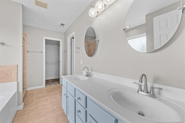 bathroom featuring tile patterned floors, visible vents, a sink, and a garden tub