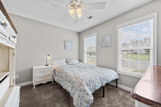 carpeted bedroom featuring baseboards, multiple windows, a ceiling fan, and visible vents