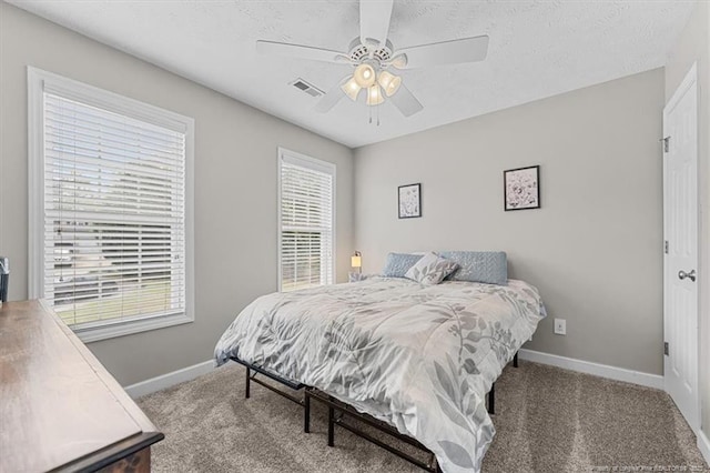 carpeted bedroom featuring baseboards, ceiling fan, and visible vents