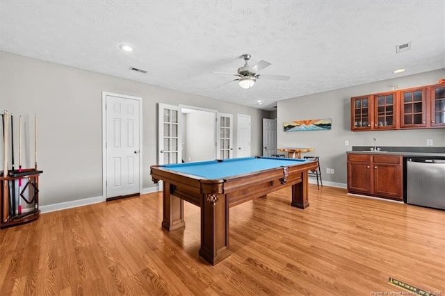 rec room featuring baseboards, light wood-style flooring, a textured ceiling, pool table, and wet bar