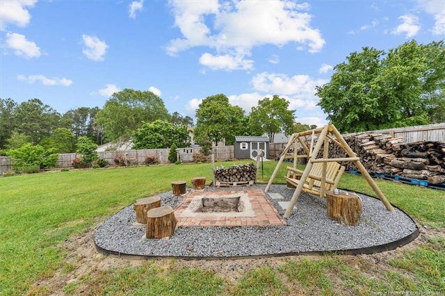 view of playground with an outdoor structure, a shed, a fenced backyard, a yard, and a fire pit