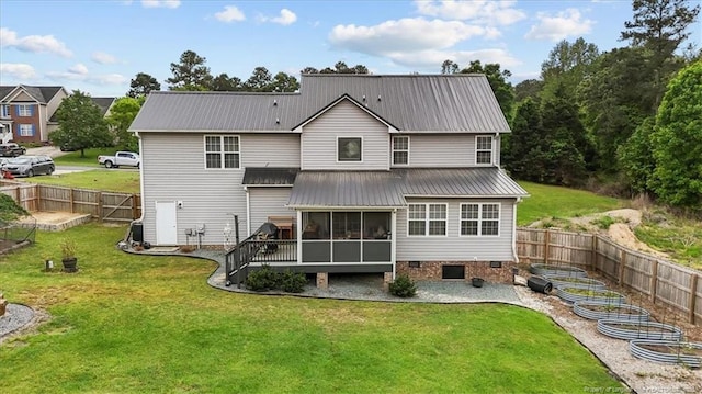 back of property featuring a yard, metal roof, a sunroom, and a vegetable garden