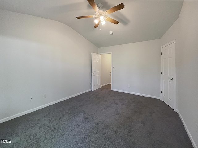 empty room featuring a ceiling fan, baseboards, lofted ceiling, and dark colored carpet