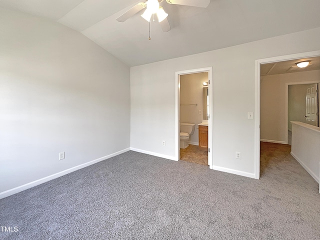 unfurnished bedroom with baseboards, ensuite bathroom, ceiling fan, carpet flooring, and vaulted ceiling