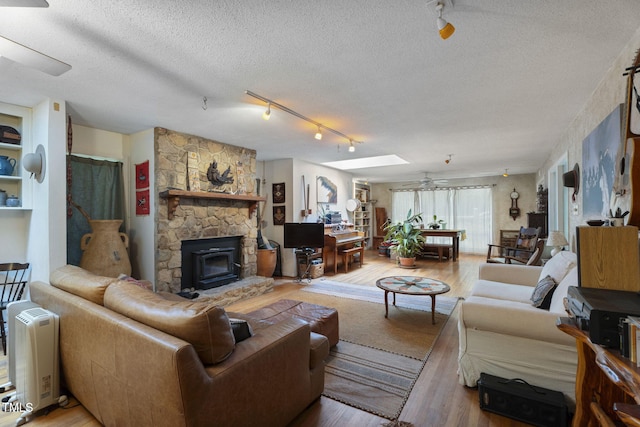 living area featuring wood finished floors, a textured ceiling, track lighting, and ceiling fan