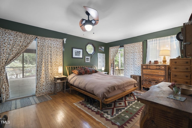 bedroom with wood finished floors, access to exterior, and a ceiling fan