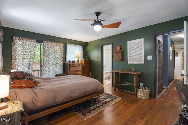 bedroom featuring wood finished floors, ensuite bath, and a ceiling fan