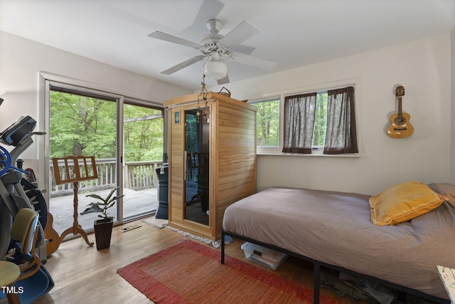 bedroom featuring access to outside, wood finished floors, and a ceiling fan