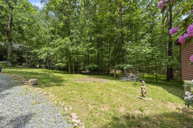 view of green lawn featuring a view of trees