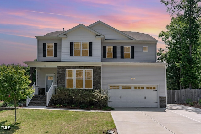 view of front facade featuring a lawn, fence, concrete driveway, an attached garage, and stone siding