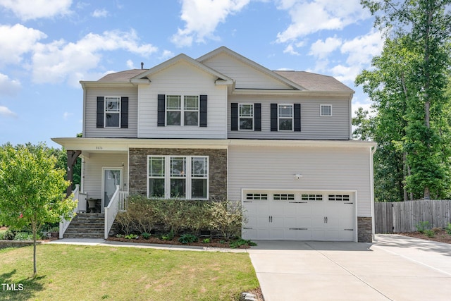 craftsman inspired home with fence, a front yard, stone siding, an attached garage, and driveway