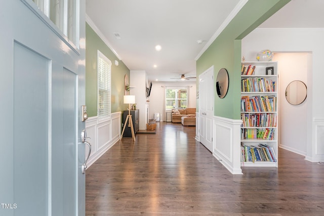 hallway with crown molding, a decorative wall, wood finished floors, recessed lighting, and a wainscoted wall