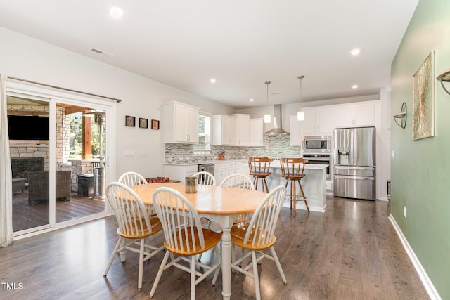 dining space featuring a stone fireplace, recessed lighting, baseboards, dark wood-type flooring, and visible vents