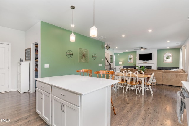 kitchen featuring a ceiling fan, wood finished floors, light countertops, white cabinets, and open floor plan