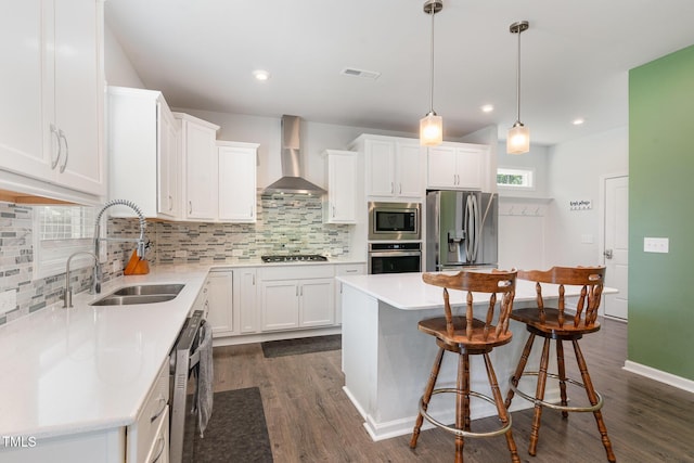 kitchen featuring wall chimney range hood, a sink, stainless steel appliances, white cabinetry, and dark wood-style floors
