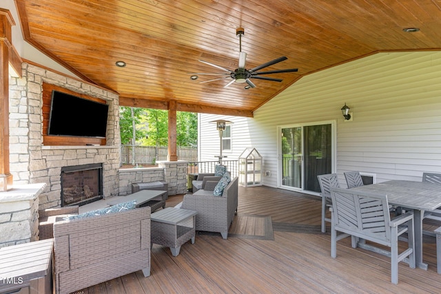 wooden terrace featuring a ceiling fan, an outdoor living space with a fireplace, fence, and outdoor dining space