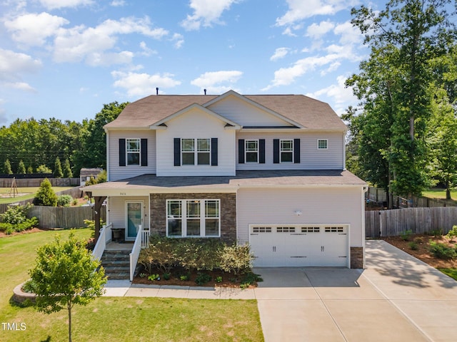 view of front of house featuring a front lawn, fence, stone siding, an attached garage, and driveway