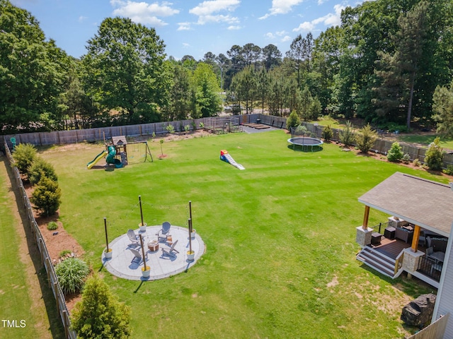 view of yard with a fenced backyard, a trampoline, and a playground