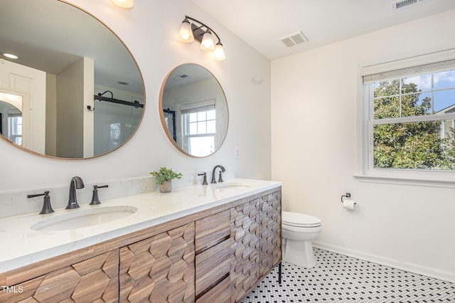 bathroom featuring toilet, an enclosed shower, double vanity, and baseboards