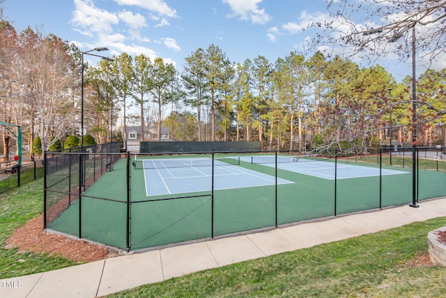 view of tennis court with fence and view of scattered trees