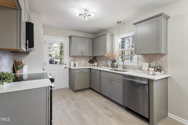 kitchen with dishwasher, gray cabinets, a sink, light wood-style flooring, and backsplash