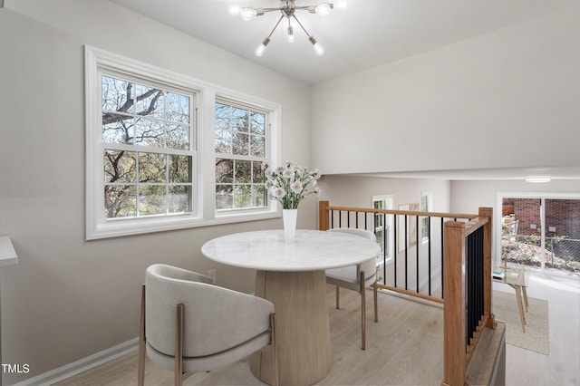 dining area featuring light wood-type flooring, baseboards, and a chandelier