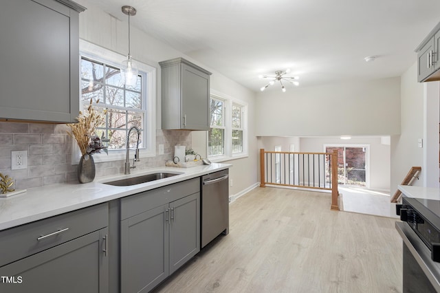 kitchen with stainless steel dishwasher, a sink, decorative backsplash, and gray cabinetry